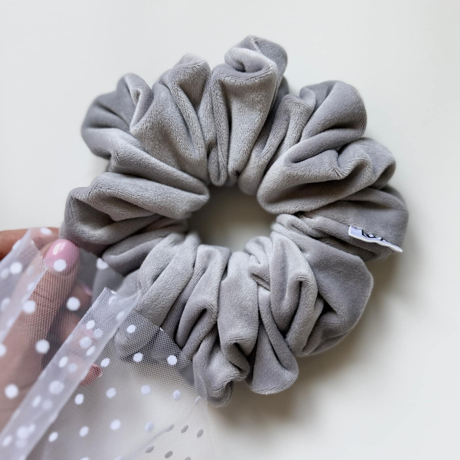 Nerida Classic Scrunchie z miękkiego weluru w kolorze szarym, delikatnie otulająca włosy, zapewniająca komfort noszenia i naturalny, lekki efekt fryzury bez ucisku i odgnieceń